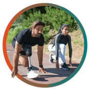 Un homme et une femme sont agenouillés en position de départ sur une piste d’athlétisme et ils se regardent.